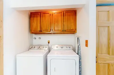 a kitchen with wooden cabinets and a washer and dryer at Wapiti Point - Main House in Grand Lake