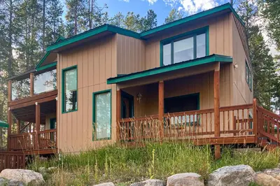 a house with a wrap around deck with trees at Wapiti Point - Main House in Grand Lake