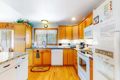 a kitchen with wooden cabinets and white appliances at Wapiti Point - Main House in Grand Lake