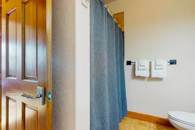 a bathroom with a toilet and a blue shower curtain at Majestic Mountain Escape in Granby